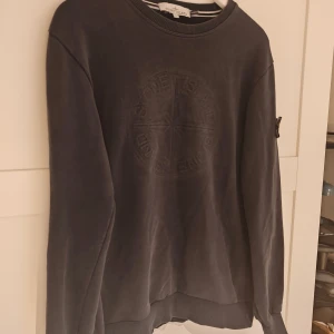 Marinblå Stone Island sweatshirt - Marinblå sweatshirt från Stone Island i slim fit med broderad logga på bröstet och klassisk patch på ärmen. Tröjan har rund hals, ribbade muddar och är tillverkad i mjuk bomull. 8/10 skick, har en vääääldigt liten skada på bakre armen som knappast märks då tröjan är väldigt mörk, kan skicka bild efter önskemål. Hör av dig om du har minsta fundering!