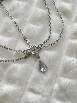 Silvrigt diadem med kedjor och berlock🤍 - Ett stilrent diadem i silverfärgad metall med tunna kedjor som hänger ner och en dekorativ berlock i form av en kristall. Diademet har en modern och edgy look, perfekt för att lyfta din outfit med en unik detalj!🩵