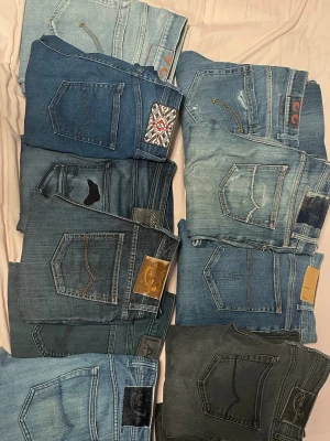 Mix av jeans i olika blå nyanser - Säljer ett gäng jeans i olika blå och svarta tvättar, flera med detaljer som broderier, patchar och kontrastsömmar. Modellerna varierar mellan raka och smala ben. Perfekt för dig som vill ha variation i garderoben och gillar klassisk denimstil.