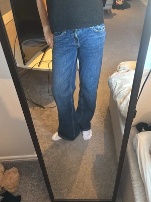 Blå raka jeans med låg midja - Säljer ett par klassiska blå jeans med rak passform och låg midja. Jeansen har fem fickor, knappgylf och är tillverkade i denim. Perfekta för en avslappnad och trendig look. Jag är 175cm och dom passar mig jätte bra! Dom är i storlek 38, men passsr mig som har 34/36🙏🏼