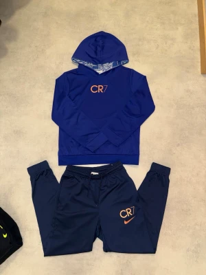 Nike CR7 dri-fit set med hoodie och byxa - Mamman köpte detta jätte snygga set till lillebrorsan som han inte tyckte om. Hade tagit på mig de själv om jag passat haha. Som sagt, han har haft på sig det en gång och det var när han skulle testa det. Möjligtvis en gång där han har blivit tvingad att ta på sig det. Han tycker den är ”konstig” och ”ingen har på sig sånt”. Pris kan diskuteras!!