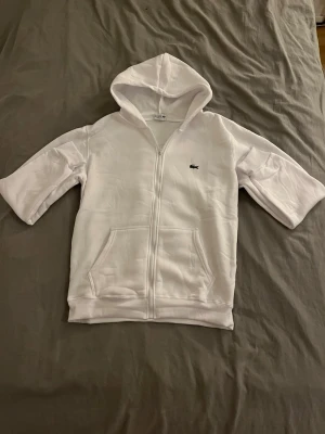 Vit zip hoodie Lacoste - Vit hoodie från Lacoste med dragkedja och huva. Perfekt för en clean och enkel stil. Skick 10/10. Storlek M/L