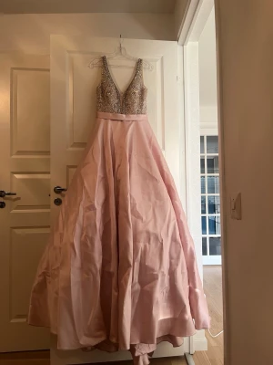 Rosa klänning - Säljer denna vackra långa klänning i ljusrosa med med paljetter och pärlor. Endast använd en kväll. Nypris 7000. 
