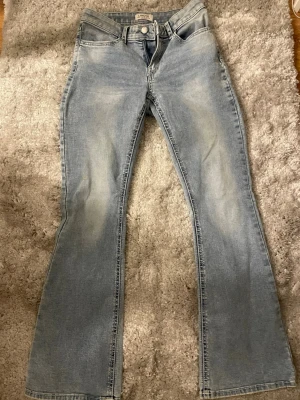 Ljusblå bootcut jeans från Lindex - Säljer ett par ljusblå bootcut jeans från Lindex med mellan hög midja, jätte fin men jag använder dom inte så ofta, jag är 154 cm och dom är lite långa men sköna och nästan oanvända. 100cm från midjan och ner, i midjan är den 39cm skriv gärna om du vill ha mer information 