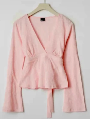 Ljusrosa omlottopp med långa ärmar - Supersöt ljusrosa omlottopp från Gina Tricot med långa ärmar och knytband i midjan. Toppen har en djup v-ringning och är gjord i ett mjukt, lätt strukturerat tyg som ger en avslappnad men ändå chic look.