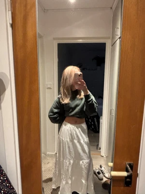 Vit långkjol med volang - Säljer en vit långkjol med volangdetaljer. Kjolen har en luftig och flowy passform som ger en avslappnad och trendig look. Perfekt för dig som gillar en enkel och stilren stil. Kjolen är tillverkad i ett lätt material!! Obs: finns en liten fläck på sömmen vid sidan! 