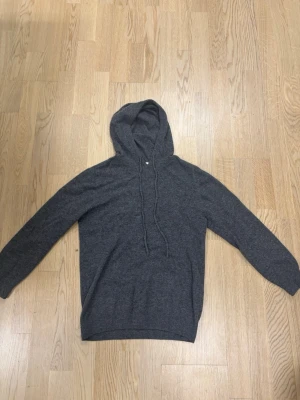 Merinoull hoodie - Mörkgrå Kashmir merinoull från Gardegrish med snören.