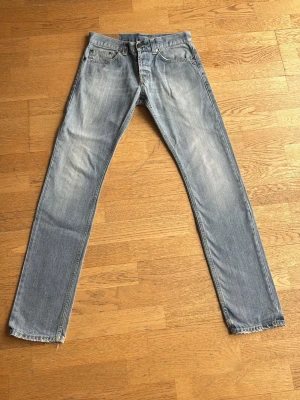 Dondup Jeans - Ljusblå jeans med små slitningar. Klassisk femficksdesign och dragkedja. Jeansen har en vintage-wash och är tillverkade i denim. Jeansen är i modellen Lucky med en Holten wash storlek 31. Hör av dig vid frågor!