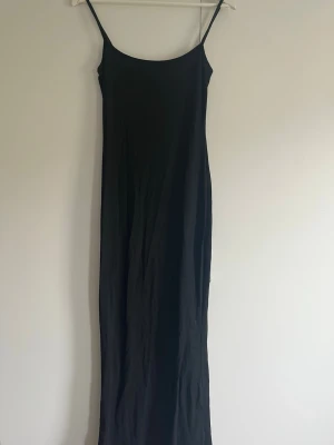 Svart långklänning med tunna band - En stilren svart långklänning med tunna axelband och rak passform. Strechig