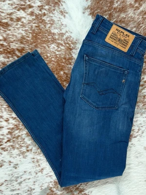 Blå jeans från Replay - Snygga blå jeans från Replay med klassisk femficksdesign och raka ben. Jeansen har en mörk tvätt med lätt slitning och detaljerad bakficka. Tillverkade i mjukt denimtyg med skinnpatch bak i midjan. Perfekta för en avslappnad och trendig look. Toppskick 9/10. Kvitto medföljer. Perfekta till våren. Bara att höra av sig vid frågor// Carl