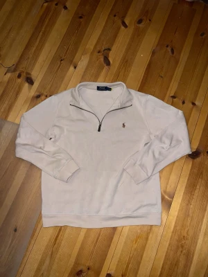 Ralph lauren quarter zip - Snygg beige quarter zip tröja från Polo Ralph Lauren med klassisk broderad logga på bröstet. Tröjan har långa ärmar, ribbade muddar och hög krage med dragkedja. Perfekt för lager-på-lager och chill stil.
