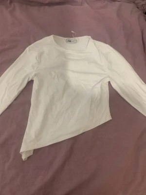 Vit långärmad topp från Faded Glory - En enkel och stilren vit långärmad topp från Faded Glory. Toppen har rund halsringning och är tillverkad i mjuk bomull, perfekt för att matcha med olika outfits. Passar dig som gillar basic-plagg med clean look.