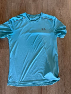 Ljusblå tränings-tshirt Under Armour - Ljusblå teknisk t-shirt från Under Armour i modellen The Tech Tee. T-shirten har korta ärmar, rund halsringning och är tillverkad i ett lätt och snabbtorkande material. Perfekt för träning och sportaktiviteter KAN PRUTA.