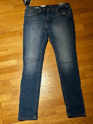 Blå slim fit jeans från Jack & Jones - Snygga blå slim fit jeans från Jack & Jones med klassisk femficksdesign och lätt tvättade detaljer. Jeansen har normal midja och raka ben. Tillverkade i mjukt denimtyg som ger en bekväm känsla och stilren look.