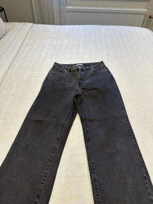 Gråa vida jeans från Lindex - Snygga gråa jeans från Lindex med vid passform och klassisk femficksdesign. Jeansen har hög midja och är tillverkade i ett mjukt denimtyg. Perfekta för en avslappnad och trendig look.