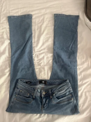 Blå bootcut jeans från LTB - Snygga blå bootcut jeans från LTB med klassisk femficksmodell och normalhög midja. Jeansen har en ljus tvätt och raka, utsvängda ben. Perfekta för en avslappnad och trendig look. Storlek 25/20. Innebenslängden 72 cm, midjemåttet 35 cm