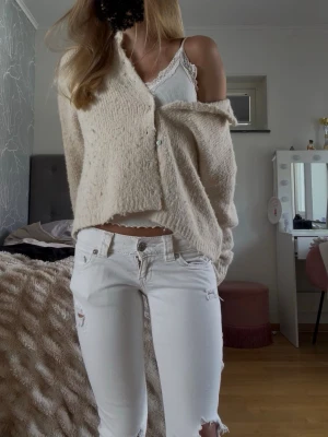 Beige fluffig kofta med knappar - Mysig beige kofta med fluffig känsla och rund halsringning. Koftan har långa ärmar och stängs med pärlemorskimrande knappar framtill. Tröjan är som man kan se lite noprig men dock var den redan noprig när jag köpte den i butik. Inget man tänker supertydligt på trots att det syns ändå. Den är inte använd mycket alls vilket noprorna talar emot. 