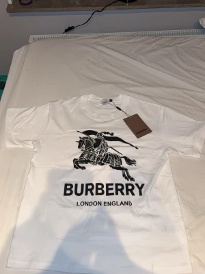 Vit bu.rberry T-shirt storlek M  - Vit bu.rberry T-shirt storlek M men tröjan är lite kort jag är 176cm lång och T-shirten är lite kort på mig. Fraktar inom 24 Tim 