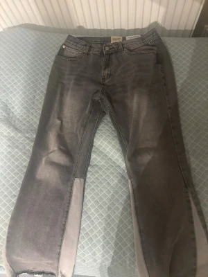 Grå jeans från Gallery Dept - Säljer ett par grå flared jeans från Gallery Dept med storlek M(W32) med raka ben och råa kanter nertill. Jeansen har en cool tvättad look och klassisk femficksdesign. Skriv för fler frågor eller bilder i chatten tack!