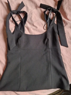 Svart Zara topp med rosetter - Trendig topp från zara med rosetter på axlarna  och dragkedja på sidan, har använts men inga skavanker💗