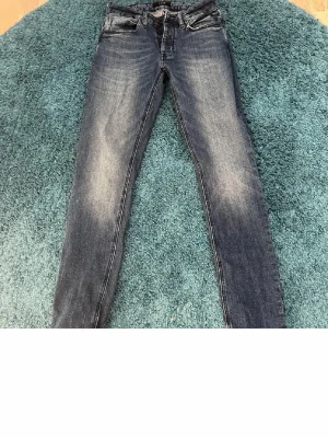 Mörkblå skinny jeans med slitningar - Säljer ett par mörkblå skinny jeans med snygga slitningar och tvättade detaljer på låren. Klassisk femficksmodell med dragkedja och knapp. Jeansen har en smal passform och är perfekta till en avslappnad stil.