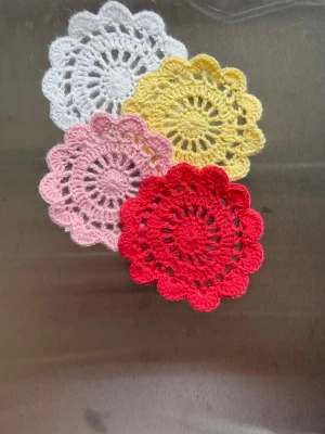 Färgglada virkade blomformade underlägg - Handgjorda virkade underlägg i form av blommor. Perfekta som accessoarer till väskor, dekoration eller som små prydnader. Tillverkade i mjukt garn med detaljerat mönster och rund form. Priset är endast för ett underlägg men man få såklart köpa fler eller be om andra färger!