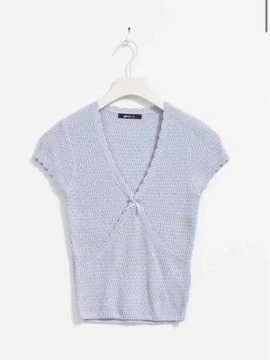 Ljusblå stickad omlottopp Gina Tricot - Supersöt ljusblå stickad topp från Gina Tricot med omlottdetalj framtill och v-ringad hals. Kortärmad och croppad modell som passar perfekt till jeans eller kjol. Mjuk och skön kvalitet med snygg struktur.