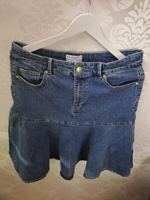 Blå jeanskjol från Holly & Whyte - Snygg blå jeanskjol från Lindex med Kjolen har är i XL men går att ha som L då den har ett stretch band, den är mid length rätt innan knänen med volanger, jättefin och söt men tyvärr aldrig kommit till användning, köpt för 400kr❤️