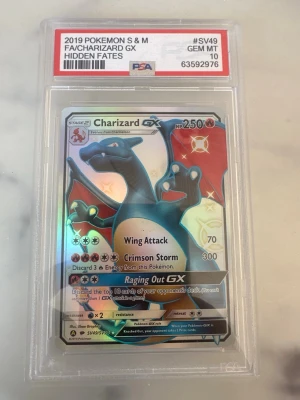 Charizard GX Hidden Fates PSA 10 - Säljer ett samlarkort, Charizard GX från Hidden Fates 2019, graderat PSA 10 GEM MT. Kortet har en holografisk yta och är inneslutet i ett skyddande plastfodral. Perfekt för Pokémon-samlare som vill ha något riktigt speciellt i sin samling.