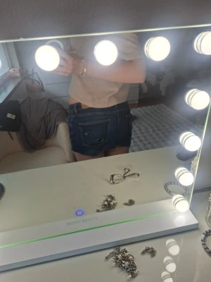 Mörkblå denimshorts med stjärndetalj - Säljer ett par mörkblå denimshorts med låg midja och råa kanter. Shortsen har en stjärndetalj på bakfickan och klassiska fickor både fram och bak. Perfekta för sommaren och ger en avslappnad vibe.