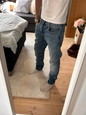 Blå Levis jeans med tvättad look - Snygga blå slim fit jeans med tvättad och något blekt look. Jeansen har klassisk femficksdesign och smal passform som sitter tajt längs benen. Perfekta för en avslappnad och trendig stil. Materialet är mjukt denim som ger bra komfort. Knappt använda, nypris ca 1700