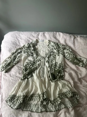 Vit och grön klänning från Zara - Supersöt kortklänning från Zara i vitt med grönt broderat mönster. Klänningen fungerar perfekt som strandklännig eller till finare tillfällen! Säljs inte längre på hemsidan! 