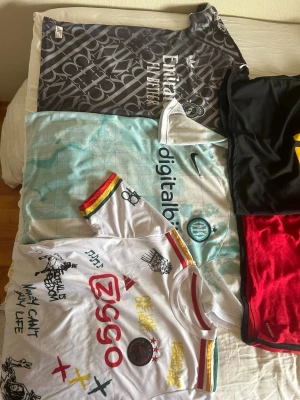 Fotbollströjor  - Säljer flera fotbollströjor: svart brasilien , ljusblå Inter från Nike, vit Ajax med graffiti-detaljer från Adidas, real madrid från Adidas med mbappe på ryggen och röd Manchester United från Adidas med garnacho på ryggen. Alla har klubbmärken, sponsorloggor och snygga detaljer. Perfekt för dig som älskar fotbollströjor! Det är flera olika storlekar, allt från 152-M så bara skriv och fråga! Även diskutera pris!