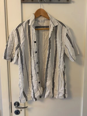 Vit kortärmad skjorta från Zara - Säljer en vit kortärmad skjorta från Zara. Perfekt för varma dagar och enkel att styla med jeans eller shorts.