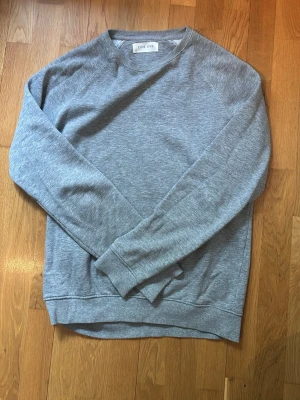 Grå sweatshirt från Pier One - En stilren grå sweatshirt från Pier One med rund halsringning och långa ärmar. Tröjan har en klassisk passform och är tillverkad i mjukt material, perfekt för en avslappnad look.