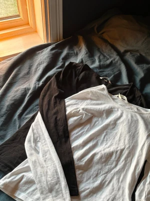 Svart och vit långärmad topp - Två långärmade toppar i svart och vitt. Klassisk rak passform med rund halsringning. Perfekta basplagg till garderoben och funkar till många olika stilar. Tillverkade i mjukt bomullstyg för skön känsla hela dagen.