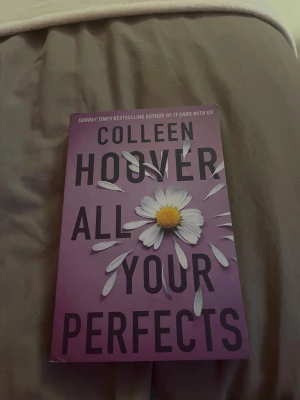 All Your Perfects av Colleen Hoover - En gripande roman av Colleen Hoover med lila omslag och prästkragar som motiv. Boken handlar om kärlek, relationer och utmaningar i ett äktenskap. Perfekt för dig som gillar känslosamma berättelser och modern skönlitteratur.