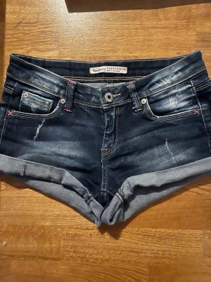 Lågmidjade jeansshorts från Pepe Jeans - Snygga mörkblå jeansshorts från Pepe Jeans med slitna detaljer. Klassisk femficksmodell, aldrig använt eftersom de inte passar. Pris går att diskutera💕