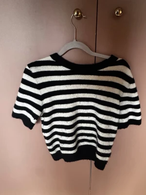 Randig stickad T-shirt  - Säljer en kortärmad, stickad topp med svartvita ränder. Från HM i strl xs
