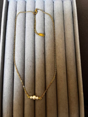 Guldhalsband med tre pärlor - Den är inte från shein jag har gjort den själv!!! Snyggt och stilrent halsband i guldfärgad kedja med tre vita pärlor i mitten. Kedjan är tunn och elegant, perfekt för att ge en subtil touch till din outfit. Låset är enkelt och smidigt att använda. Passar dig som gillar minimalistiska smycken.