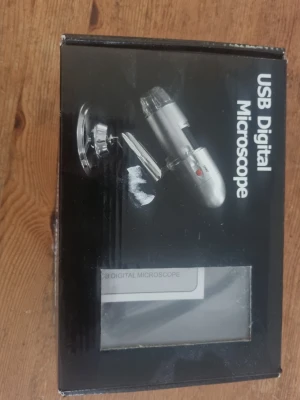 USB Digitalt Mikroskop - USB digitalt mikroskop i silverfärg med stativ och USB-kabel. Perfekt för att undersöka små detaljer på datorn. Mikroskopet har en kompakt design och levereras i originalförpackning med tillhörande manual.