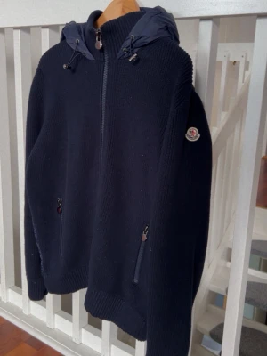 Moncler cardigan  - Snygg mörkblå pufferjacka från Moncler med stickade ärmar och vadderad kropp. Jackan har huva med dragsko, två fickor med dragkedja och Moncler-logga på ärmen. Perfekt för kyliga dagar och riktigt trendig look. Kan gå ner i pris vid snabb o smidig affär, skriv gärna innan om man ska köpa🤝