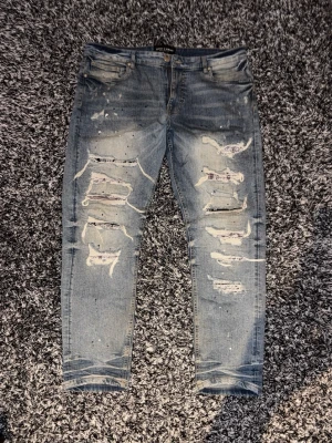 Slim fit jeans - Säljer ett par ljusblå jeans med kraftiga slitningar och stora hål framtill. Jeansen har slim fit. Dom är använda men är inte sönder någonstans. Pris går att diskutera 