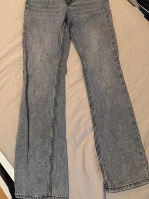 Ljusblå raka jeans - Säljer ett par ljusgråa  jeans med rak passform och klassisk femficksdesign. Jeansen har medel midja och är tillverkade i denim med en lätt tvättad look. Perfekta för en avslappnad och trendig stil.