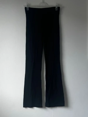 Svarta utsvängda leggings - Säljer ett par svarta leggings med låg midja fold over och utsvängda ben. De är stretchiga och sitter tajt upptill men blir vidare nedtill, vilket ger en snygg siluett. Perfekta att styla med en oversized hoodie eller crop top.