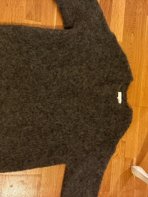 Mörkgrå fluffig alpacka tröja NA-KD - Mysig mörkgrå alpacka tröja från NA-KD med fluffig yta. Tröjan har en enkel, rak passform och långa ärmar. Perfekt för kalla dagar när du vill ha något både snyggt och bekvämt.
