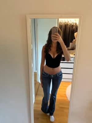 Festtopp  - Snygg svart sammet croppad korsettopp med djup v-ringning och breda axelband. Toppen har en tight passform och är perfekt för att skapa en trendig look. Passar till både jeans och kjol för en cool outfit.