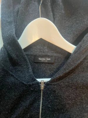Mörkgrå hoodie från Massimo Dutti - Snygg mörkgrå hoodie från Massimo Dutti med dragkedja framtill och huva. Tillverkad i mjukt material som känns skönt mot huden. Perfekt för dig som gillar en stilren och enkel look. Passar till det mesta och är lätt att matcha.