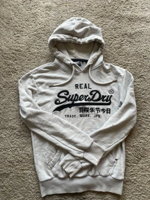 Ljusgrå hoodie från Superdry - Säljer en  hoodie från Superdry Storlek S . Skicket är helt okej då den har några enstaka hål i sig, kan skicka bilder på hålen privat om man vill köpa  öppen för bud såklart!😀