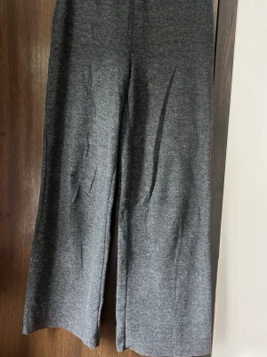 Mörkgrå vida byxor - Mörkgrå mjukisbyxor med breda ben och hög midja. Tillverkade i ett mjukt, lätt stretchigt material som känns riktigt skönt mot huden. Perfekta för chill dagar hemma eller när du vill ha en avslappnad look. Inga synliga loggor eller detaljer.
